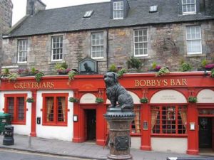 The statue above a fountain of Bobby, facing the Churchyard of Greyfriars, with the more recent addition bearing his name in the background.